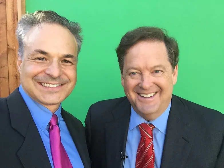 Two men smiling in front of green screen.